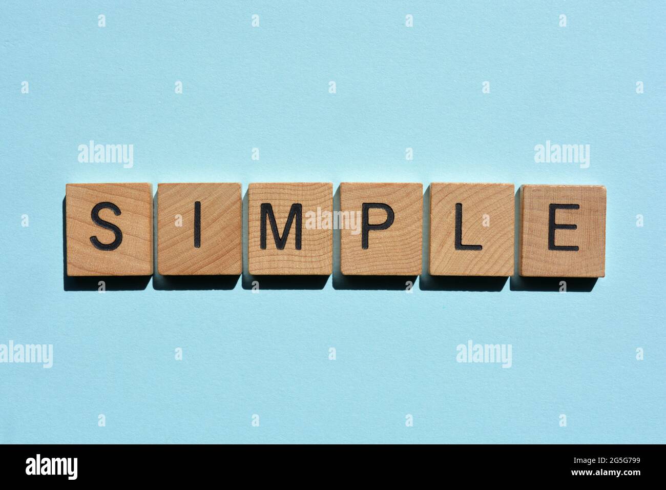 Semplice, parola in lettere alfabetiche in legno isolato su fondo blu chiaro Foto Stock