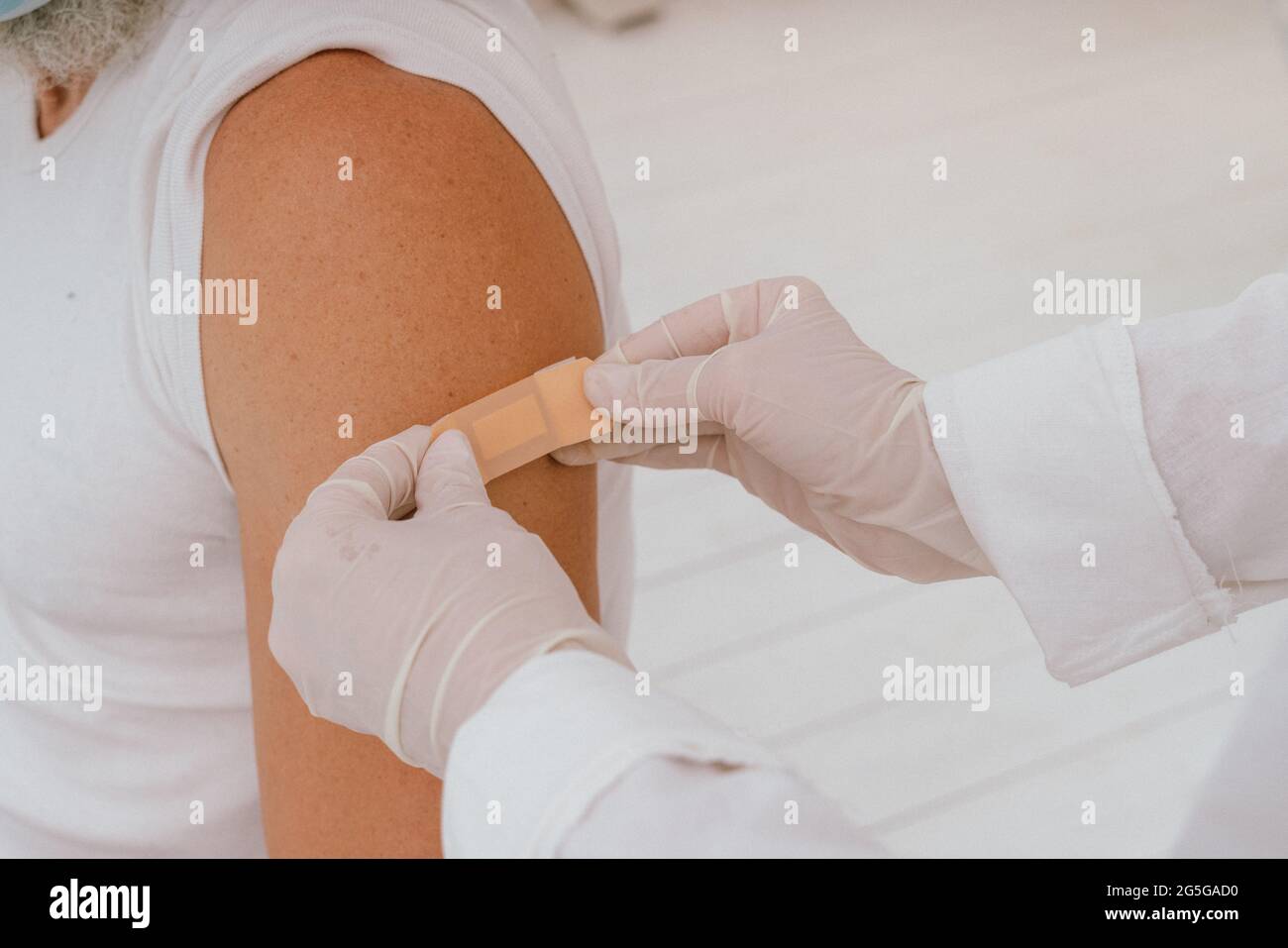 il medico applica un cerotto al paziente dopo il vaccino covid-19 Foto Stock