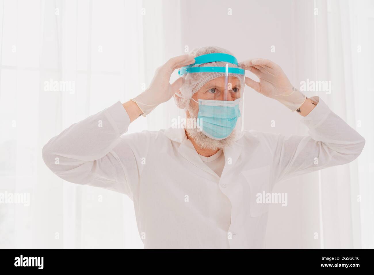 Medico con maschera e protezione del viso è pronto a lavorare in ospedale Foto Stock