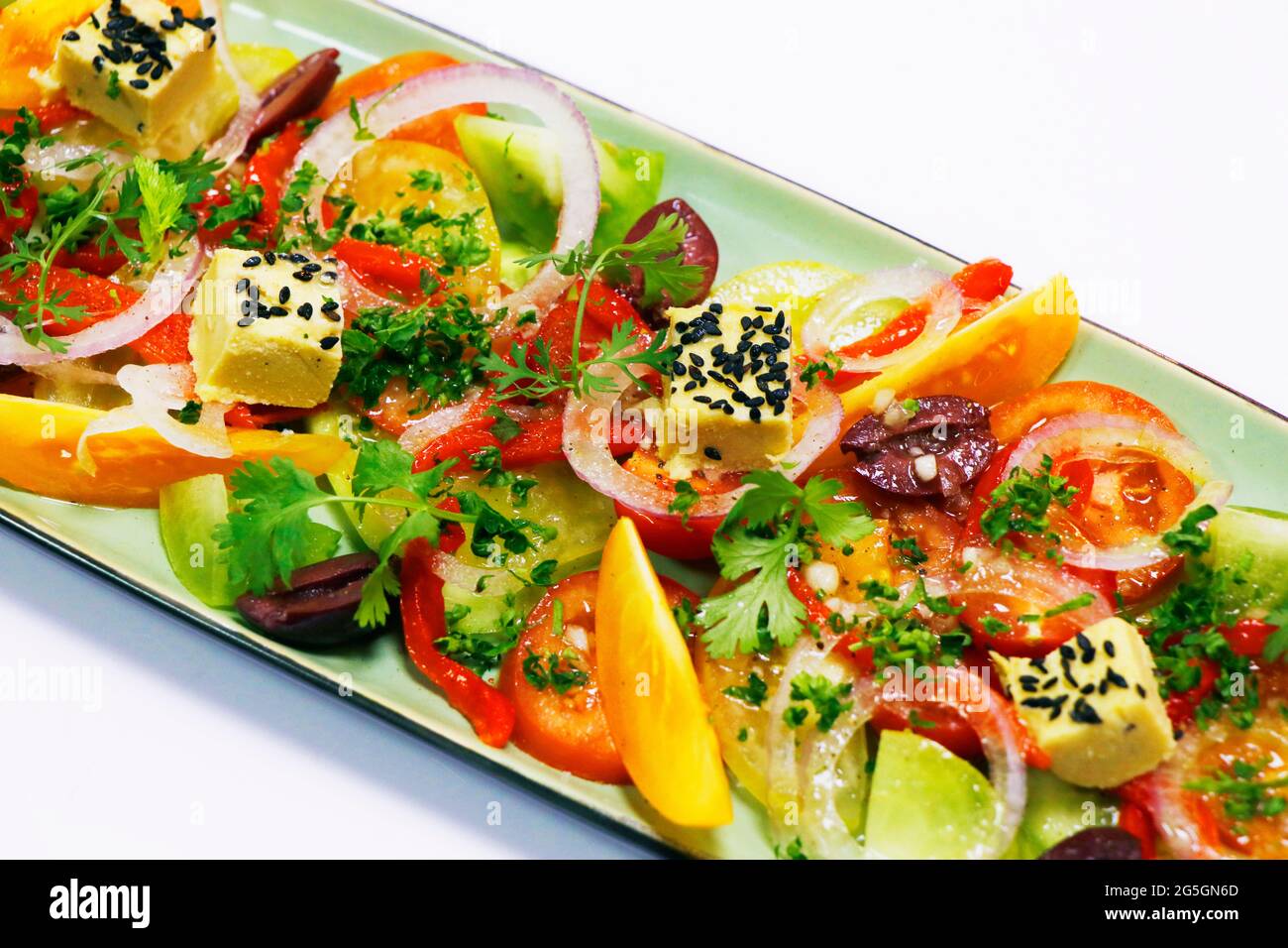 insalata di pomodoro di primo piatto in stile mediterraneo con cipolle, olive, erbe e formaggio Foto Stock
