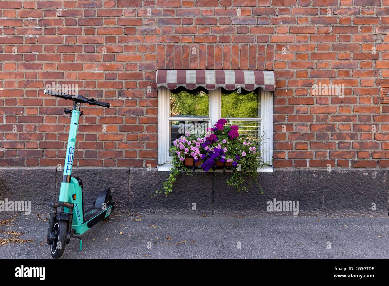 Immagine ravvicinata dello scooter elettrico parcheggiato di fronte all'edificio in mattoni rossi Foto Stock