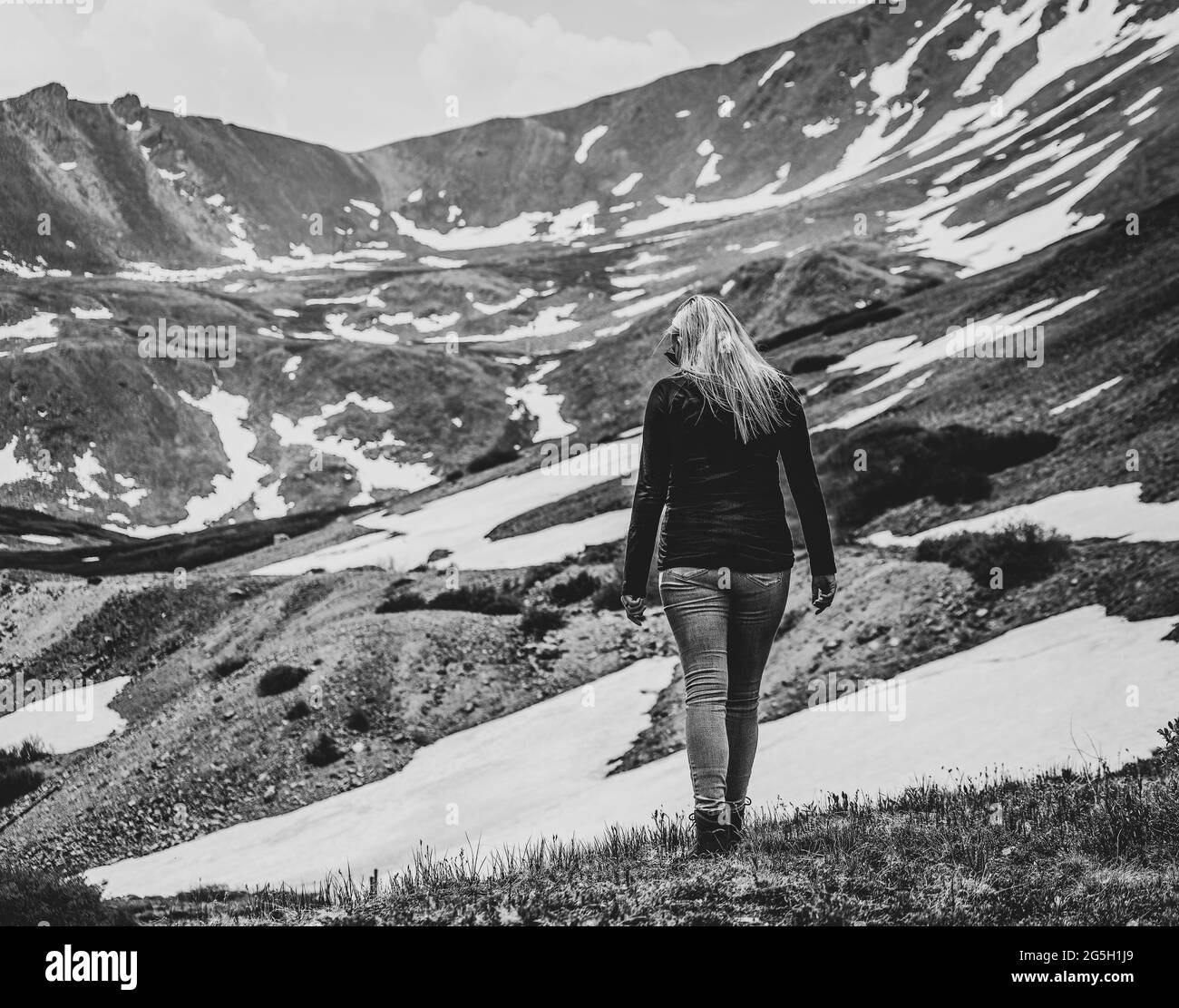 Immagine in bianco e nero di una bella donna che si snoda lungo l'alta cima della montagna Foto Stock