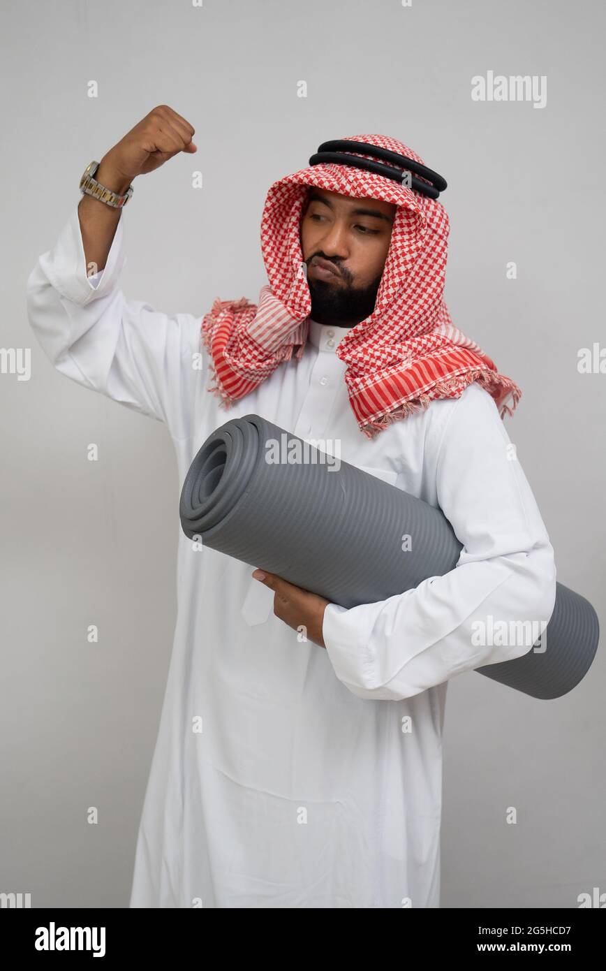 Un uomo arabo che indossa un turbante sente lo spirito di aggrovagliare il  pugno verso l'alto mentre porta un tappetino Foto stock - Alamy