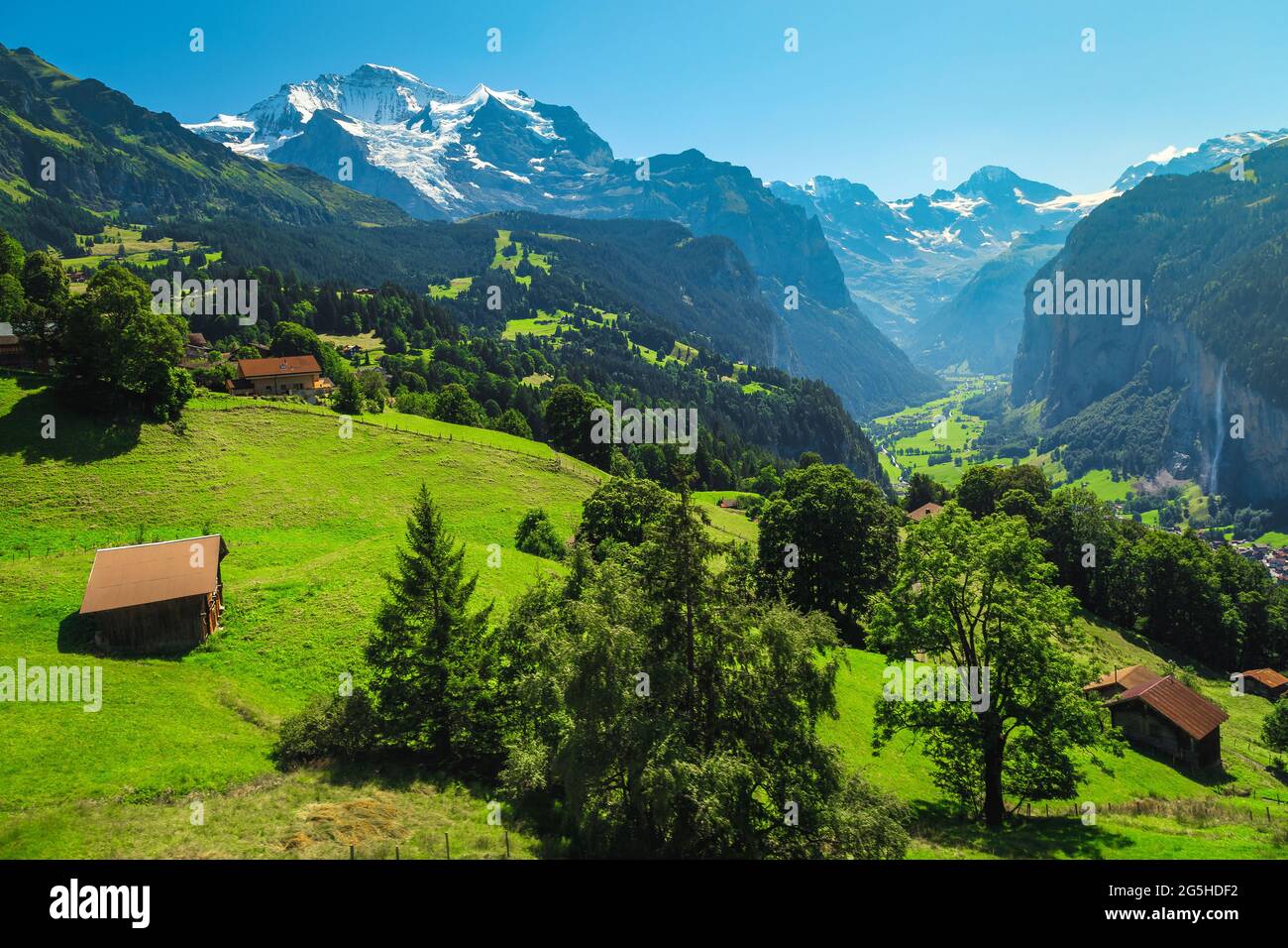 Splendide piste alpine estive con prati verdi e montagne innevate. Località turistica di Wengen e villaggio di Lauterbrunnen nella valle profonda, Bernese o Foto Stock