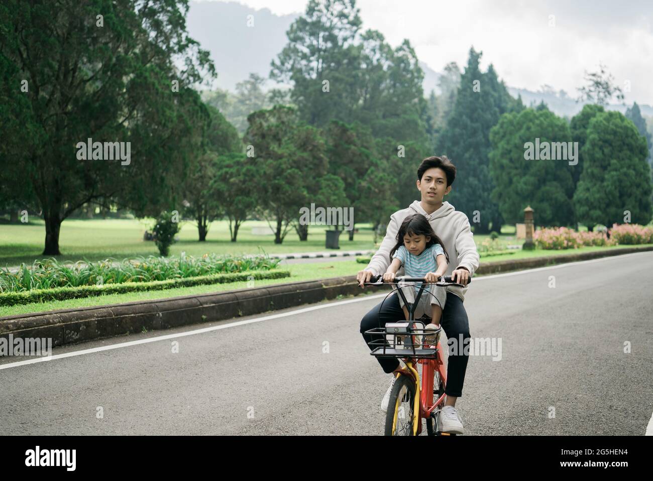 fratello prende sua sorella in divertente bicicletta a cavallo nel parco Foto Stock
