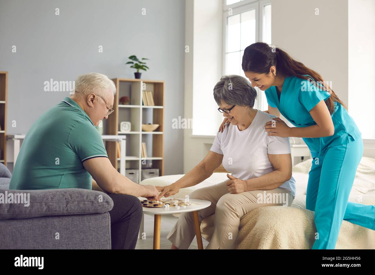 I pensionati felici dell'anziano e della donna hanno divertimento giocando i giochi da tavolo nella casa di cura. Foto Stock