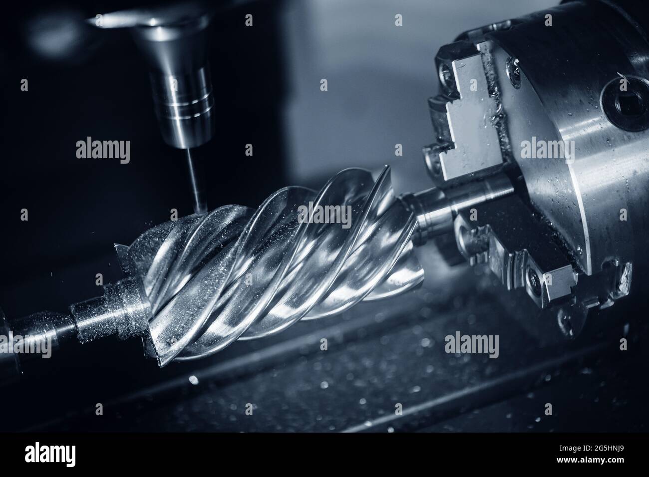 La fresatrice CNC lavora parti di vite senza fine in acciaio con trucioli metallici, background industriale. Foto Stock