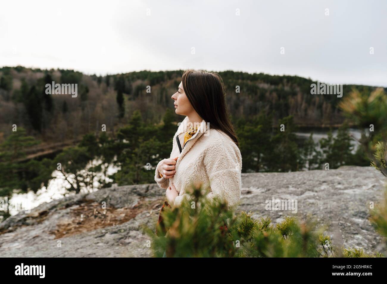 Giovane donna che guarda via mentre si sta in montagna durante la vacanza Foto Stock