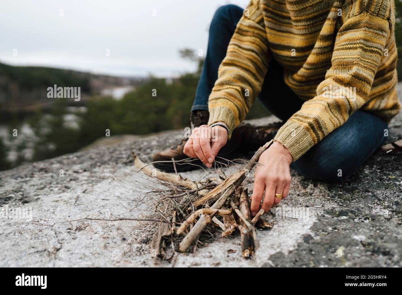 Sezione bassa di donna con bastoni che preparano il fuoco di montagna Foto Stock