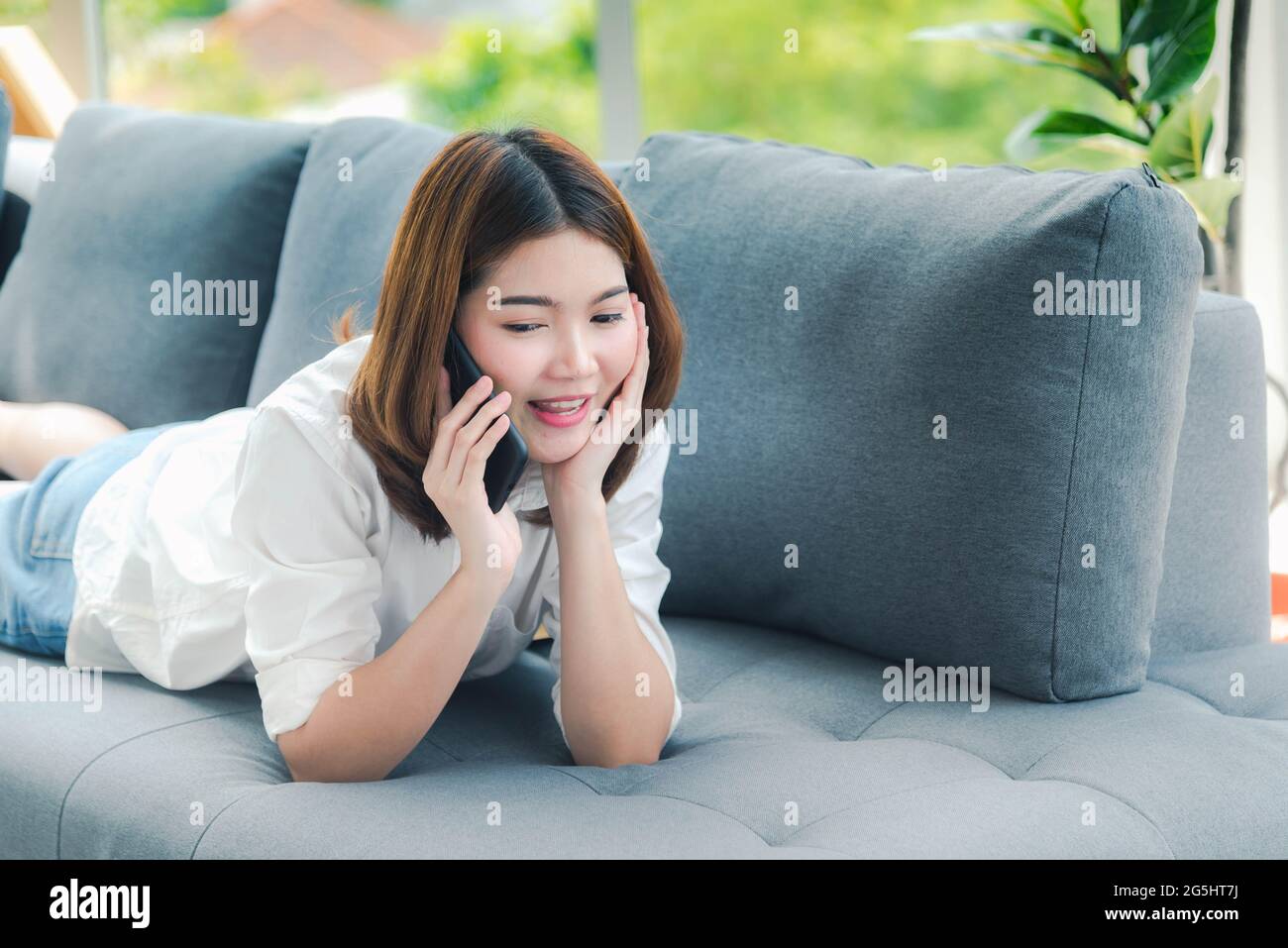 sullo smartphone. Faccia sorridente della donna asiatica che tiene il cellulare con e-commerce Shopping online sito web che legge articolo online, blog e vlog. Foto Stock