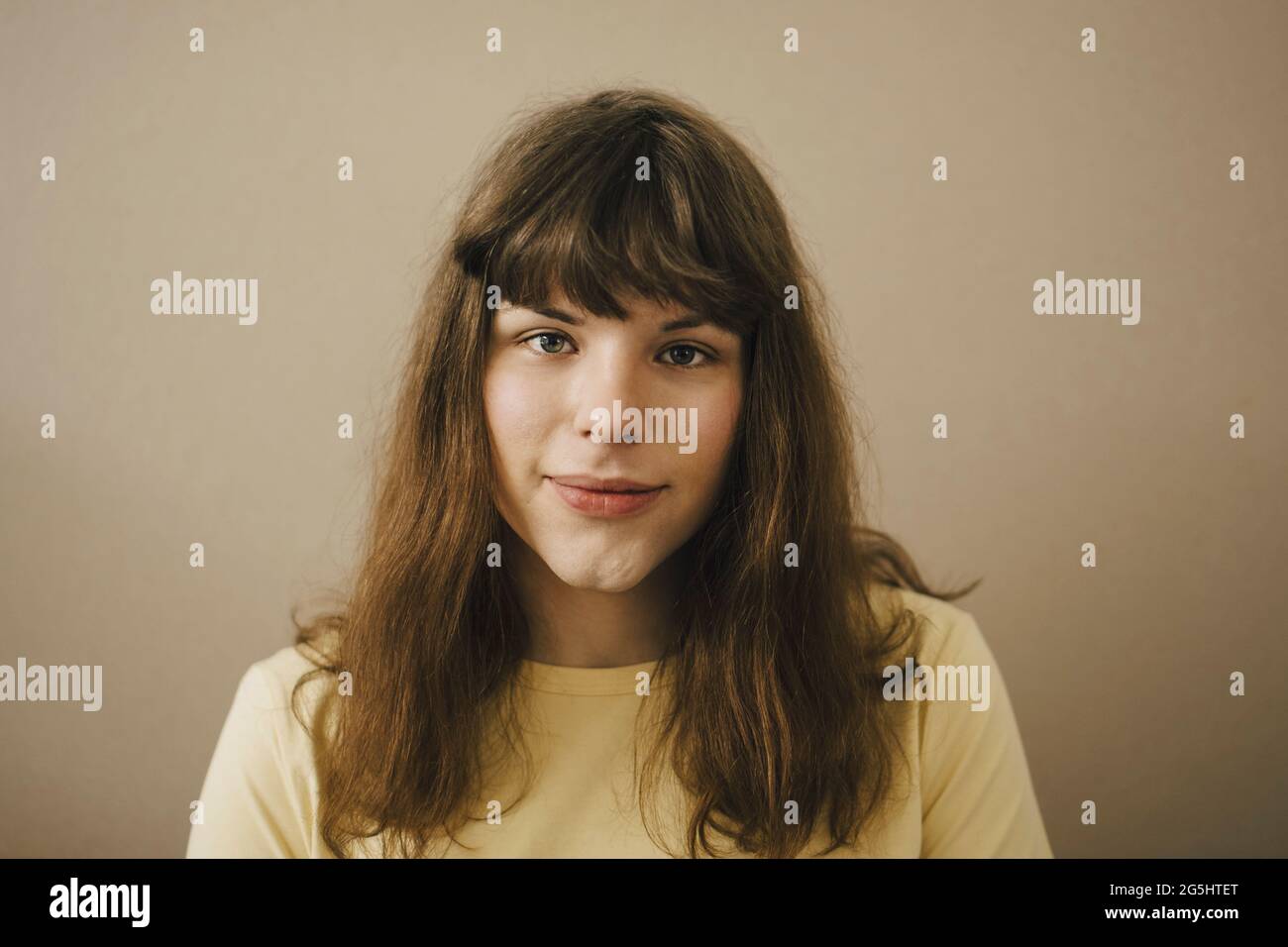 Ritratto di giovane donna con pangs su sfondo beige Foto Stock