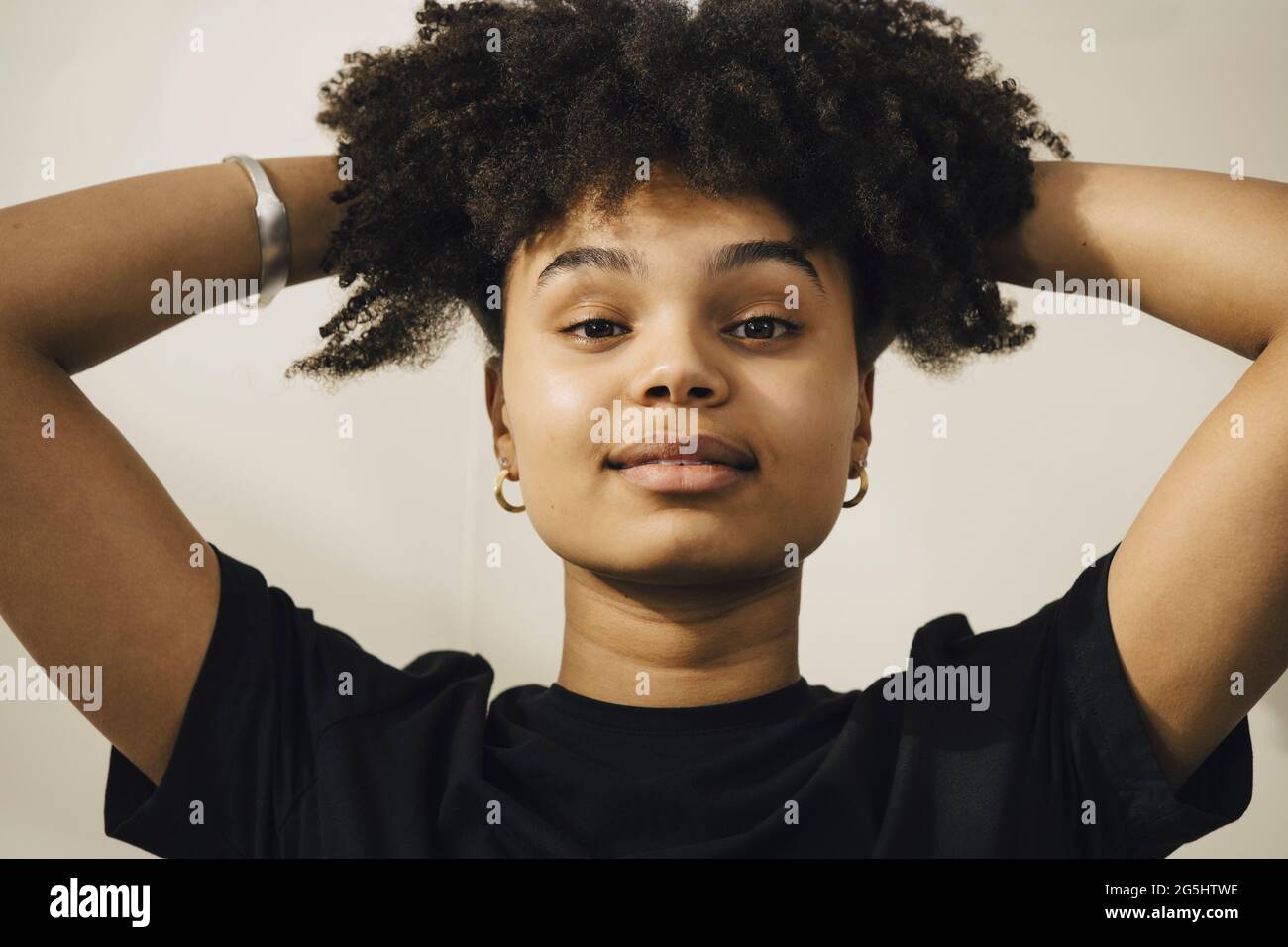 Giovane donna con la mano in capelli su sfondo beige Foto Stock