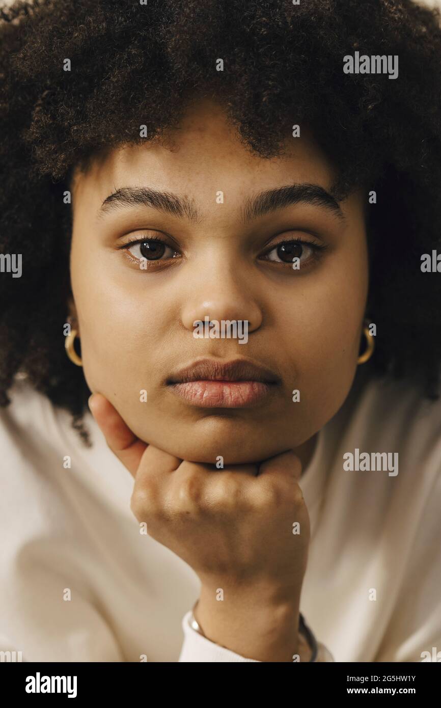 Ritratto di donna dai capelli ricci con mano sul mento Foto Stock