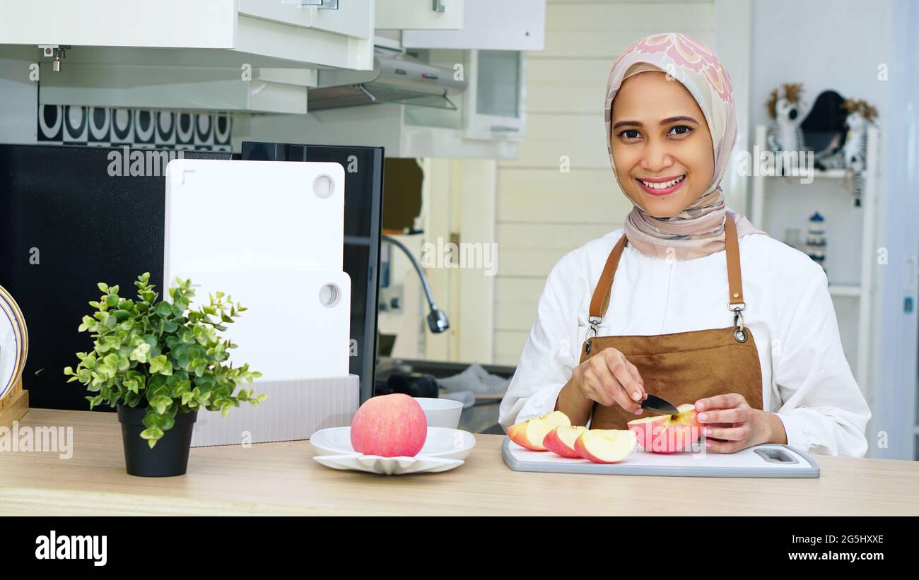Donna musulmana che indossa Hijab con grembiule in cucina Foto Stock