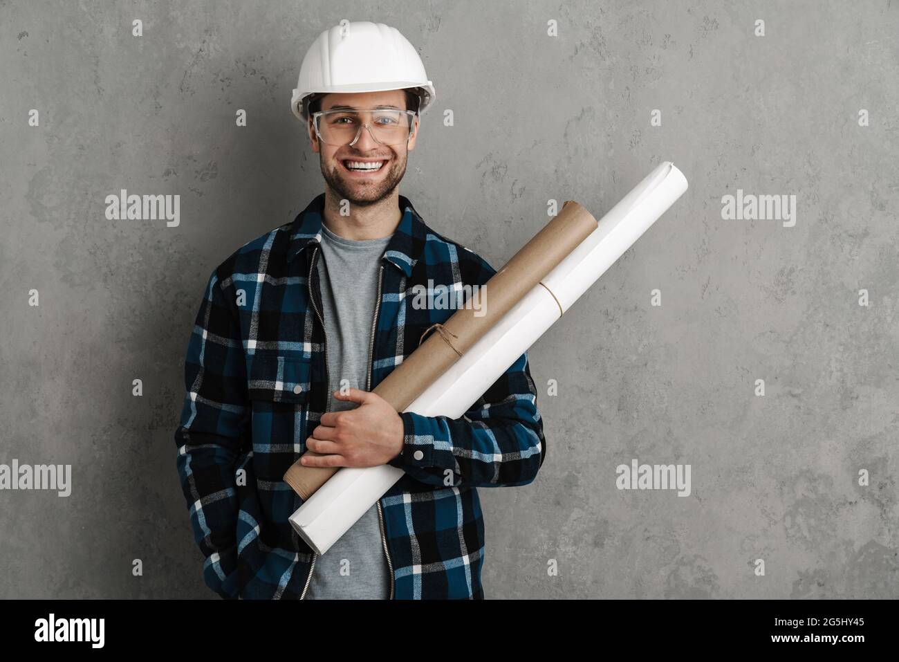 Giovane bell'ingegnere civile in hardhat che tiene progetti isolati su sfondo grigio Foto Stock