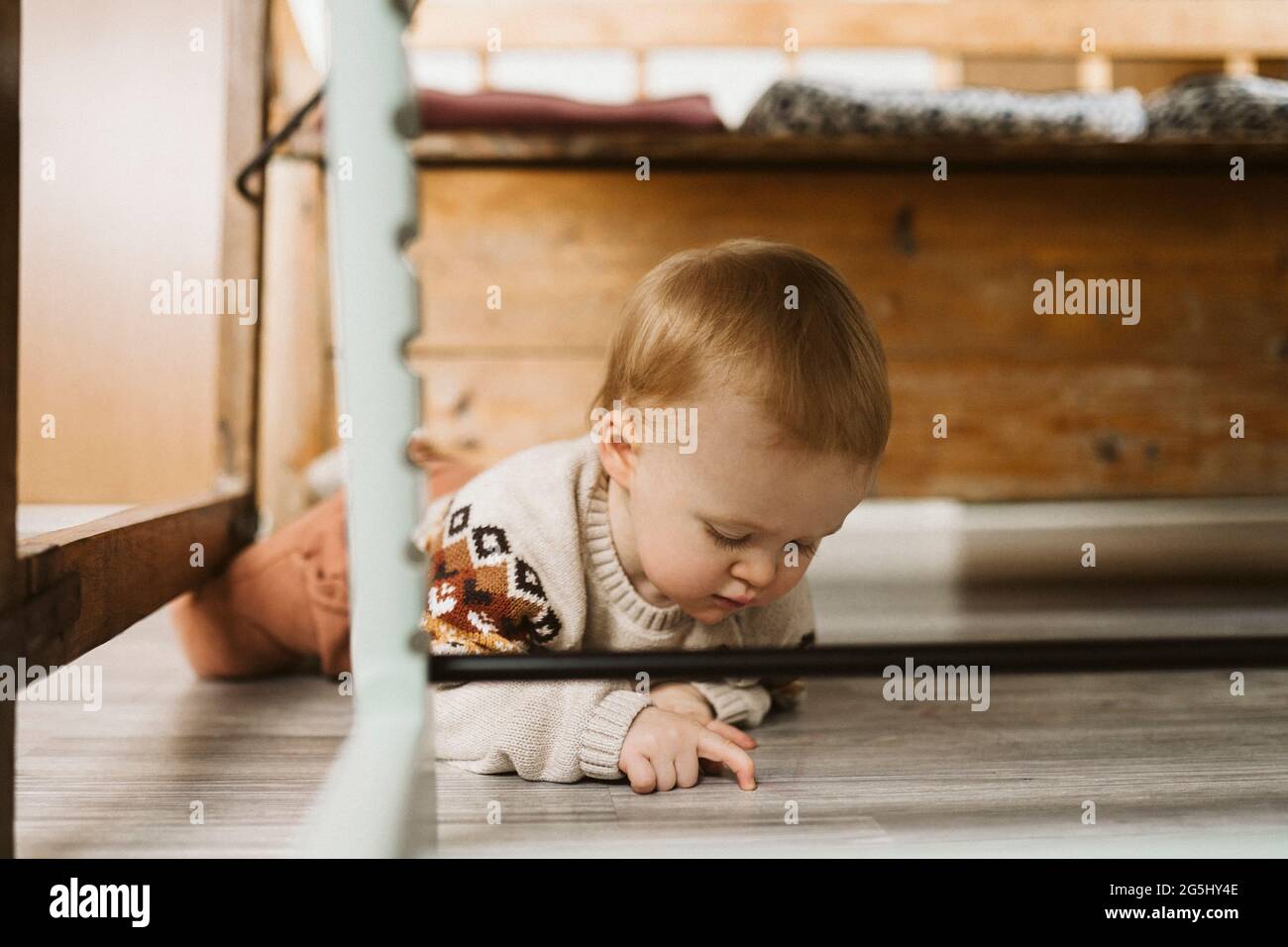 Ragazza curiosa che gioca mentre si trova sul pavimento a casa Foto Stock
