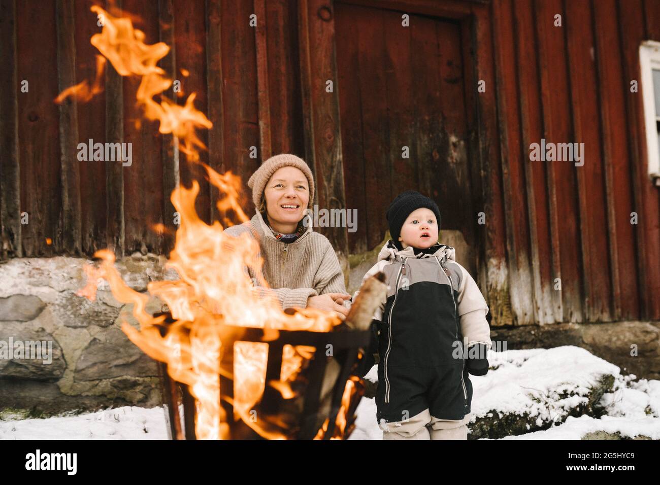 Madre con la figlia vicino bruciando la fossa di fuoco che guarda via Foto Stock