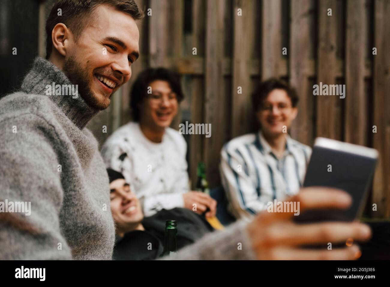 Amici maschi felici che prendono selfie attraverso il telefono cellulare in balcone Foto Stock