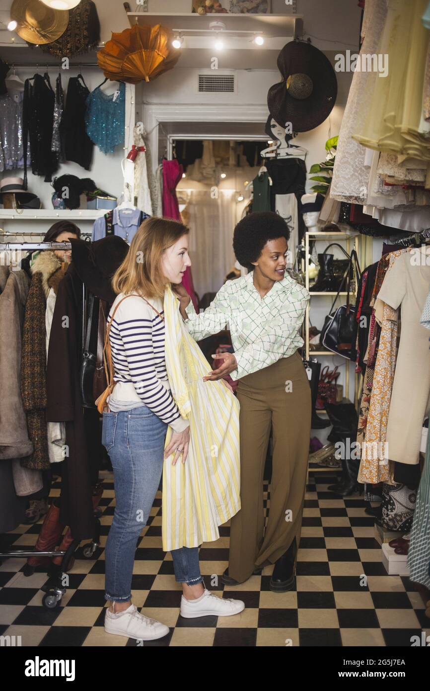 Proprietario africano provando abito su cliente femminile in negozio di abbigliamento Foto Stock