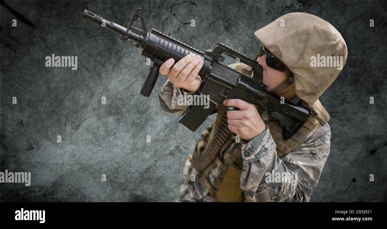 Composizione di soldato maschio che indossa occhiali da sole puntando pistola, contro fumo su nero Foto Stock