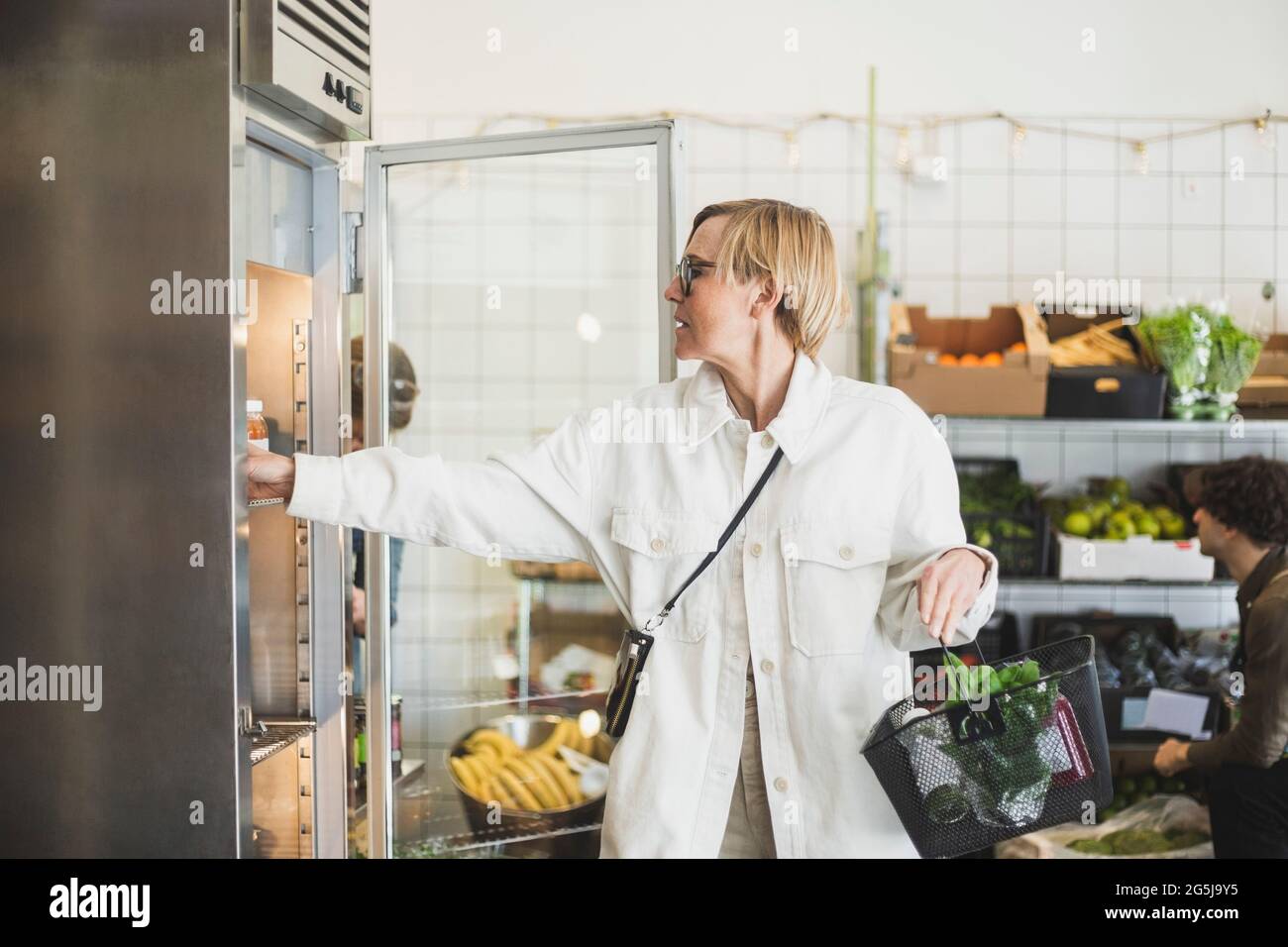 Donna matura bionda che acquista cibo dal negozio Foto Stock