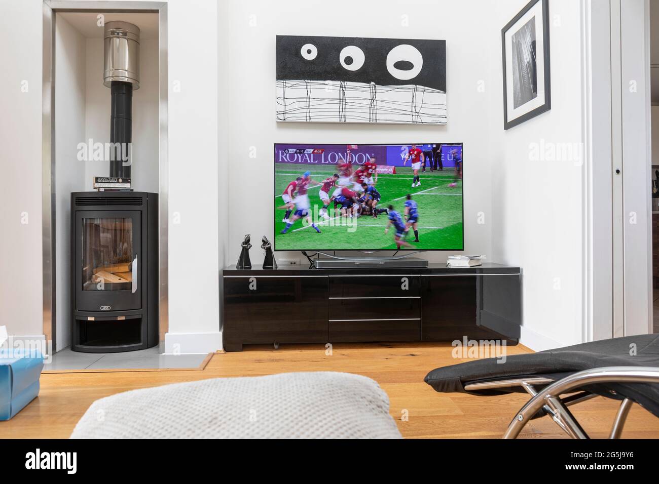 Una vista su un salotto moderno con una partita di rugby sul televisore Foto Stock