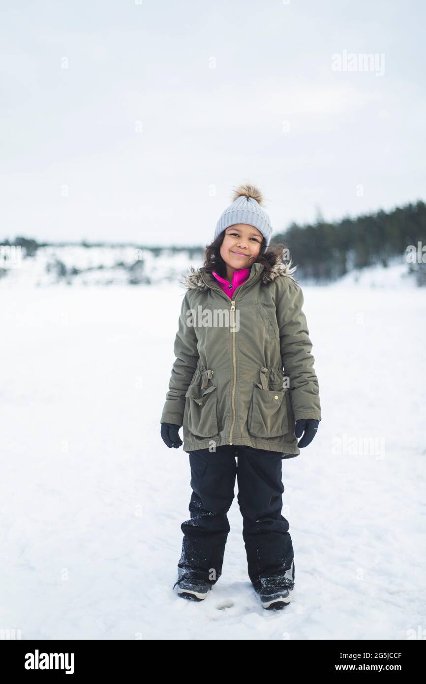 Tutta la lunghezza della ragazza sorridente in piedi sulla neve Foto Stock