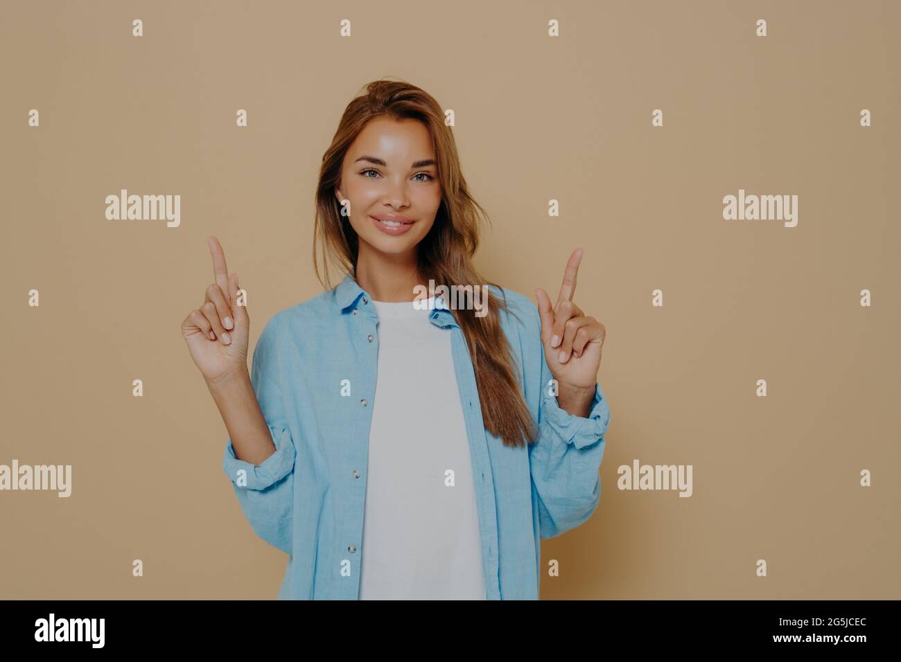 Elettrizzato ragazza europea allegra con lunghi capelli brunette che indossano abiti casual in posa in studio Foto Stock