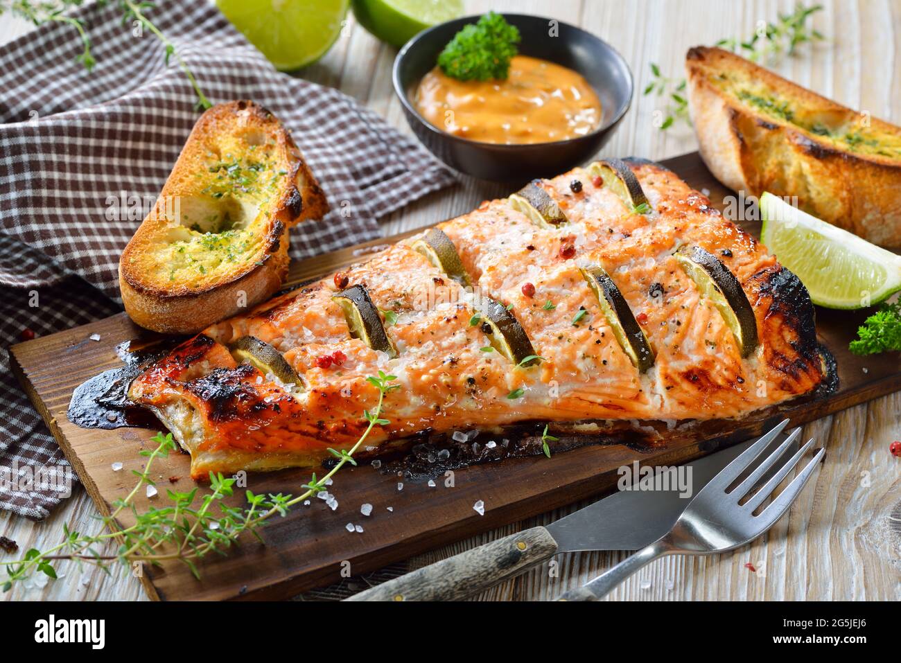 Filetto di salmone succoso con fette di lime su una tavola di legno di cedro alla griglia fresca dal grill del bollitore Foto Stock