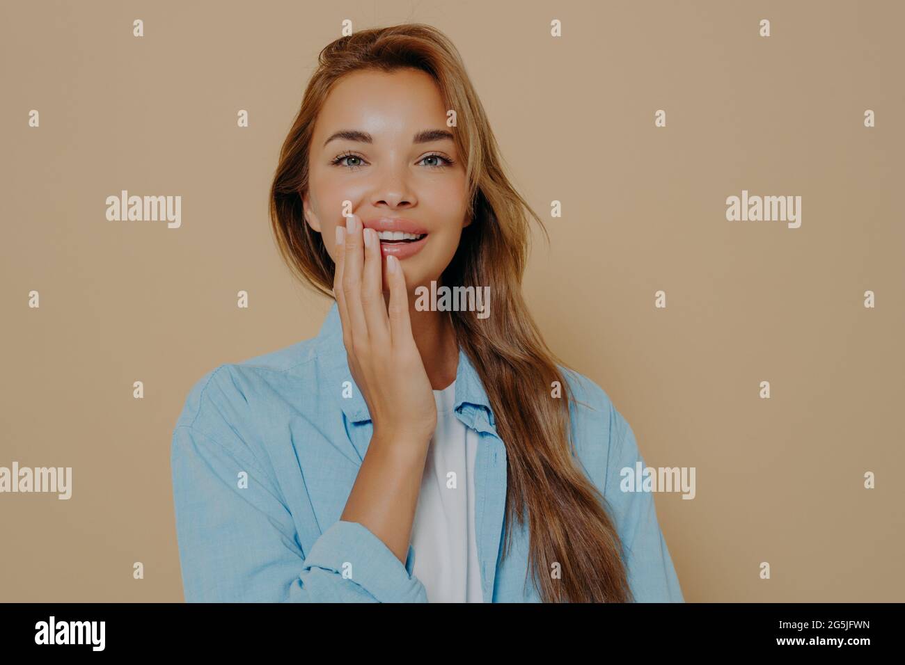 Affascinante donna tenera tocca delicatamente la guancia con la mano sullo sfondo dello studio Foto Stock