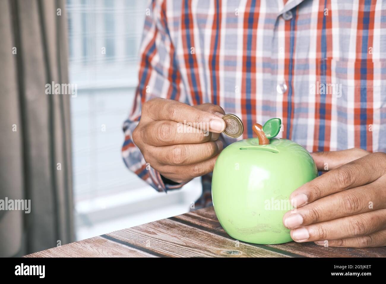 giovane uomo che salva le monete in un vaso mentre è situato Foto Stock