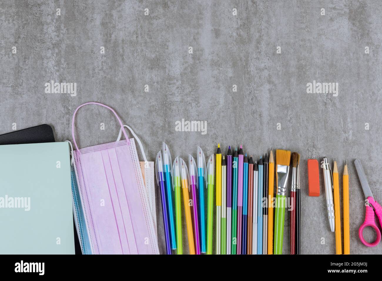 Attrezzature di cancelleria in assortimento di vari articoli di forniture scolastiche sui tempi di scuola l'appartamento si trova in maschere mediche sul covid-19 coronavirus Foto Stock