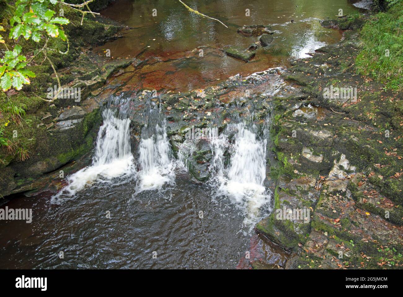 Acqua che scorre su una piccola cascata, a Neath, Galles. Presa con un'esposizione più lenta per catturare il movimento dell'acqua. Foto Stock