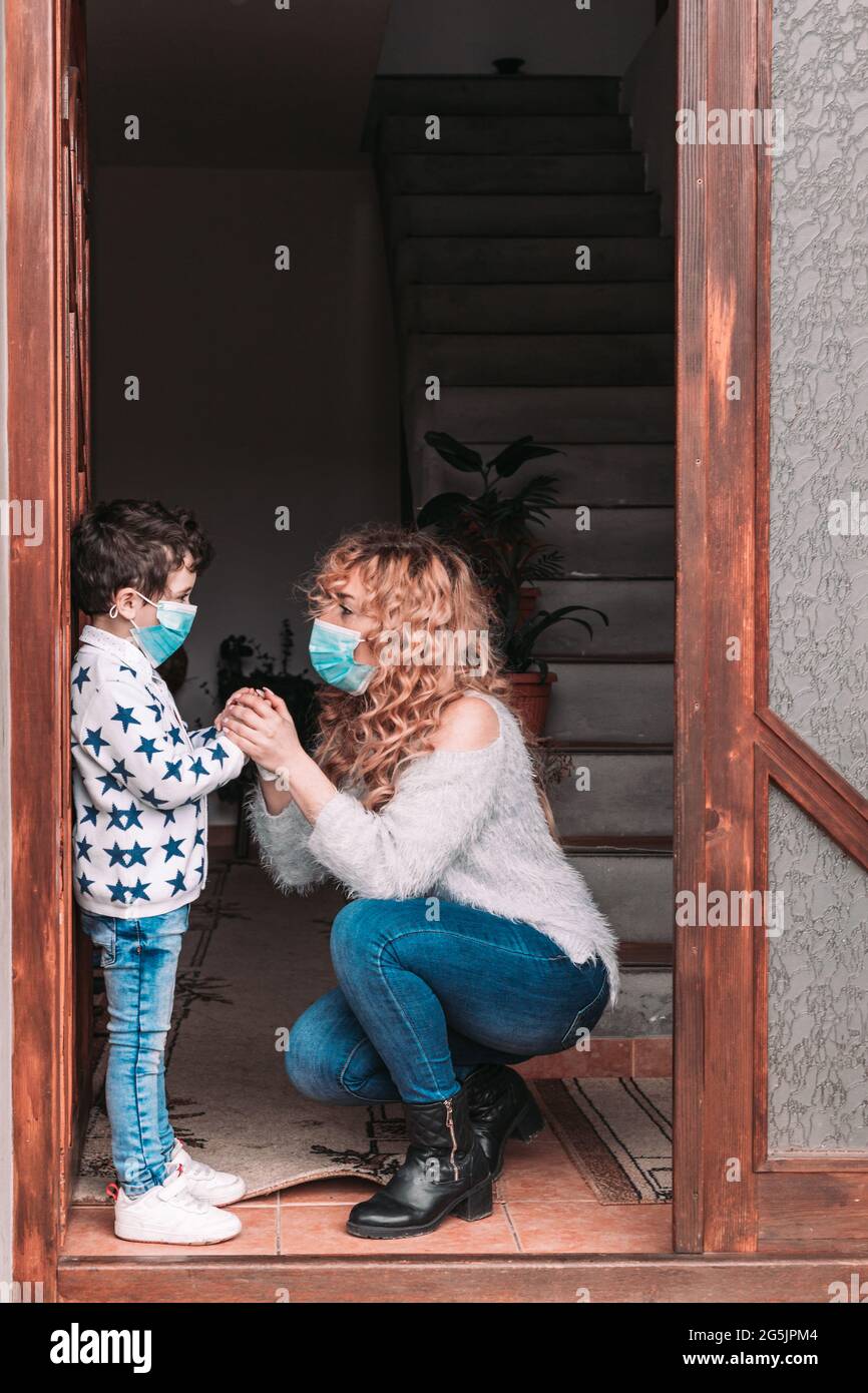 Mamma e suo figlio del bambino indossano maschere facciali che si preparano per uscire Foto Stock