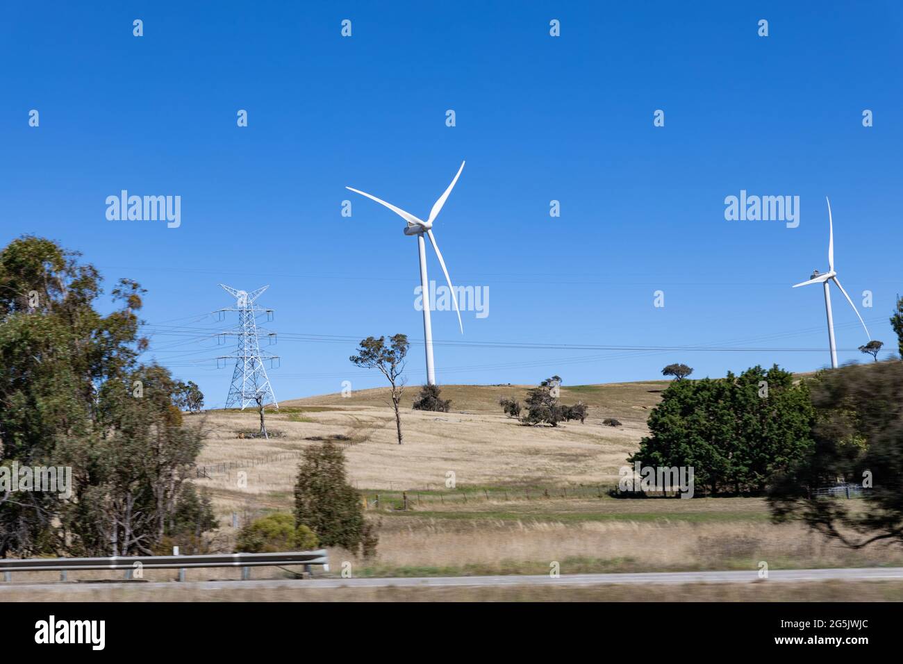 Elettricità che genera il mulino a vento Farms Hume Highway NSW Australia preso da auto in movimento sfocato primo piano Foto Stock