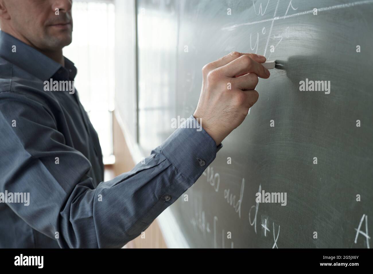 Insegnante contemporaneo con pezzo di formula di scrittura gesso su lavagna Foto Stock