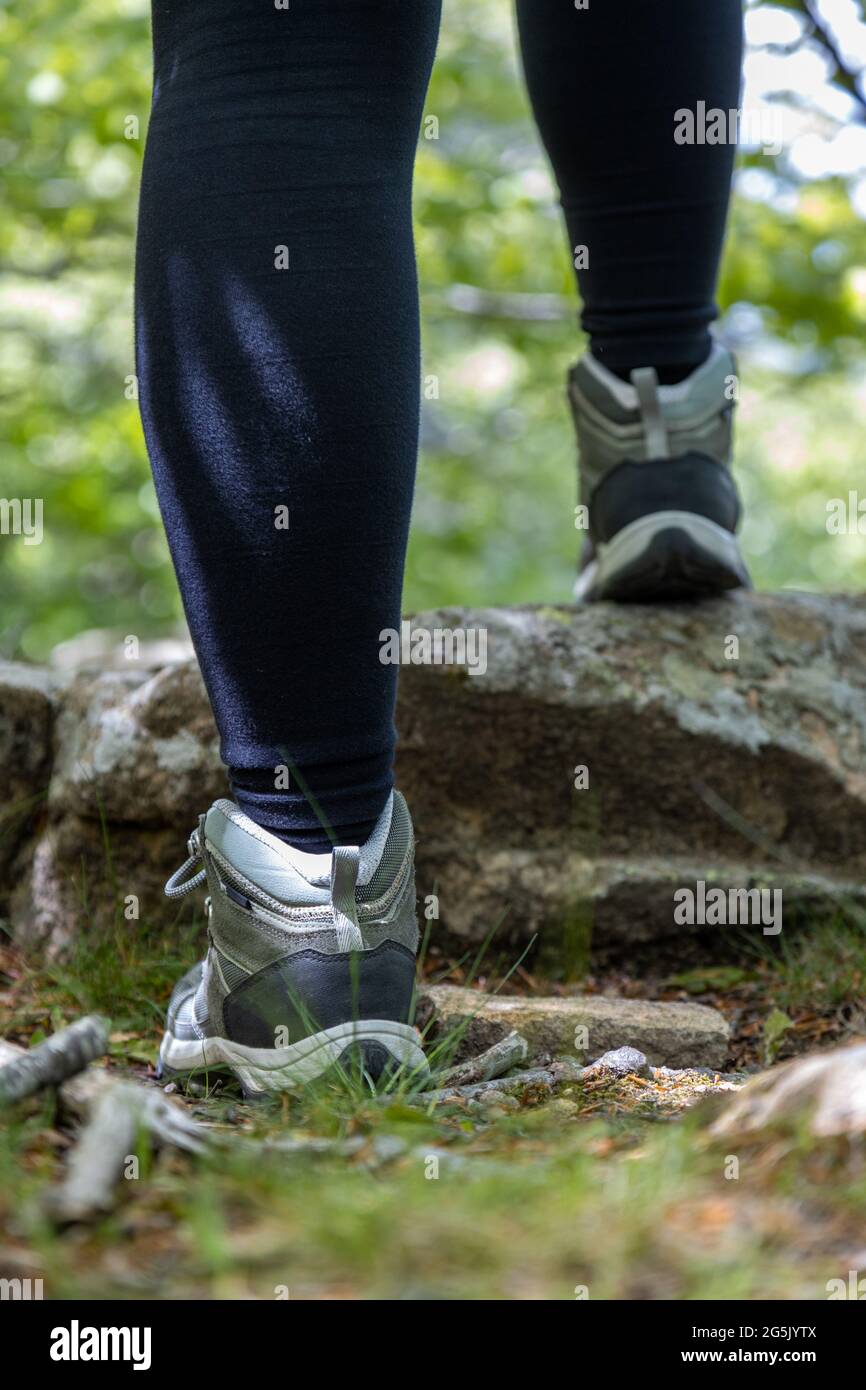 Scarpone di escursionista su sentiero forestale. I piedi del viaggiatore stanno salendo sulla roccia. Avventura e concetto di escursioni all'aperto. Stile di vita hipster Foto Stock