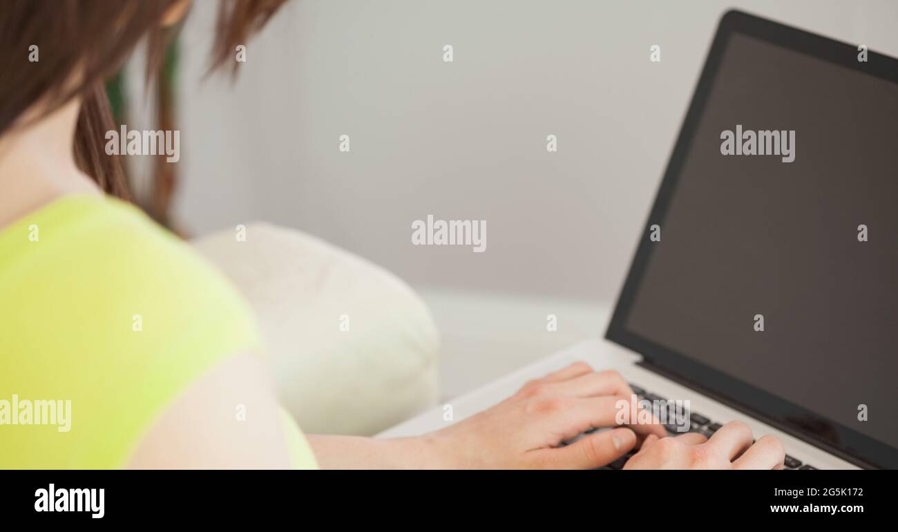 Vista sulla spalla di una donna che utilizza un computer portatile Foto Stock