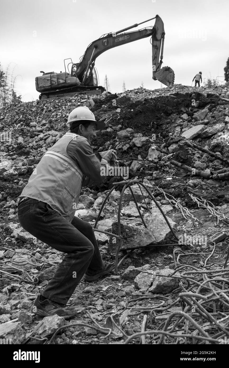 Il lavoratore di costruzione raccoglie i pezzi di metallo dalle macerie Foto Stock