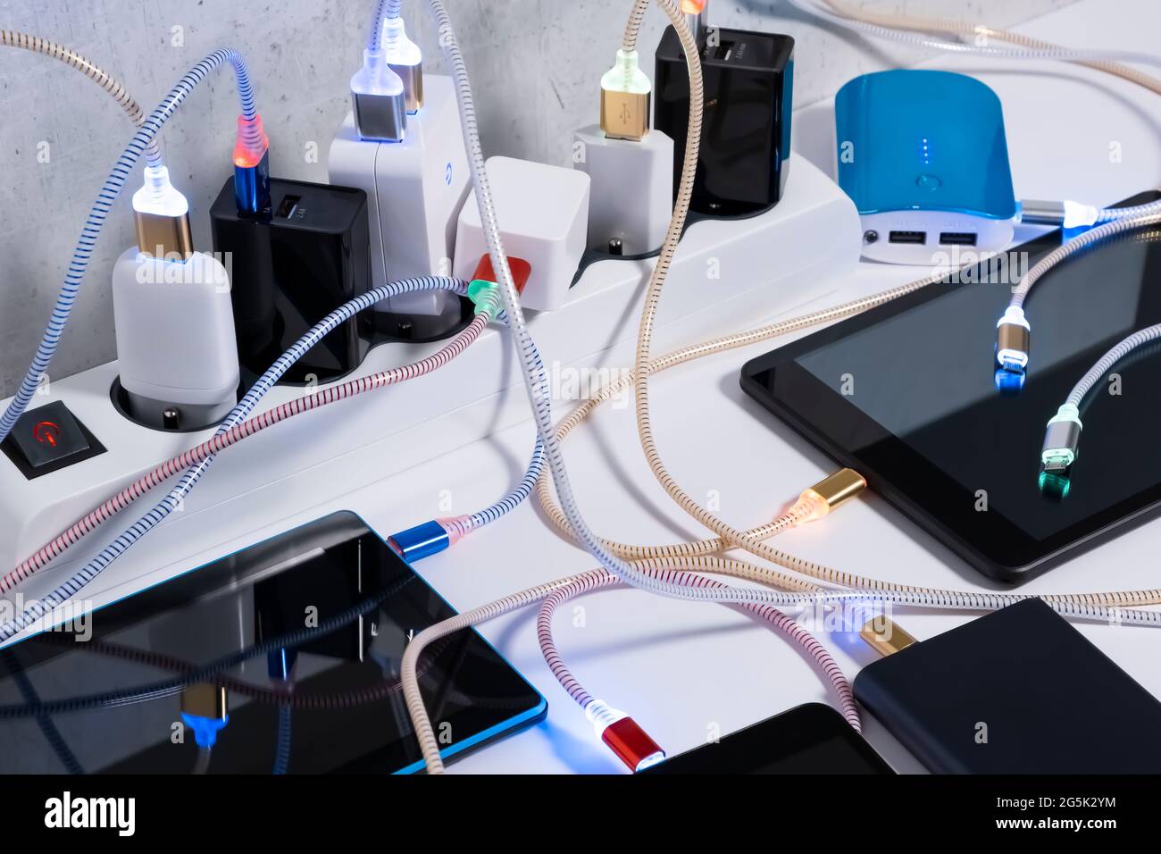 Telefono cellulare e tablet smartphone collegati all'hub di ricarica sul tavolo, cavi micro usb ai caricabatterie nelle prese. Interruttore cavo di prolunga caricato con Foto Stock