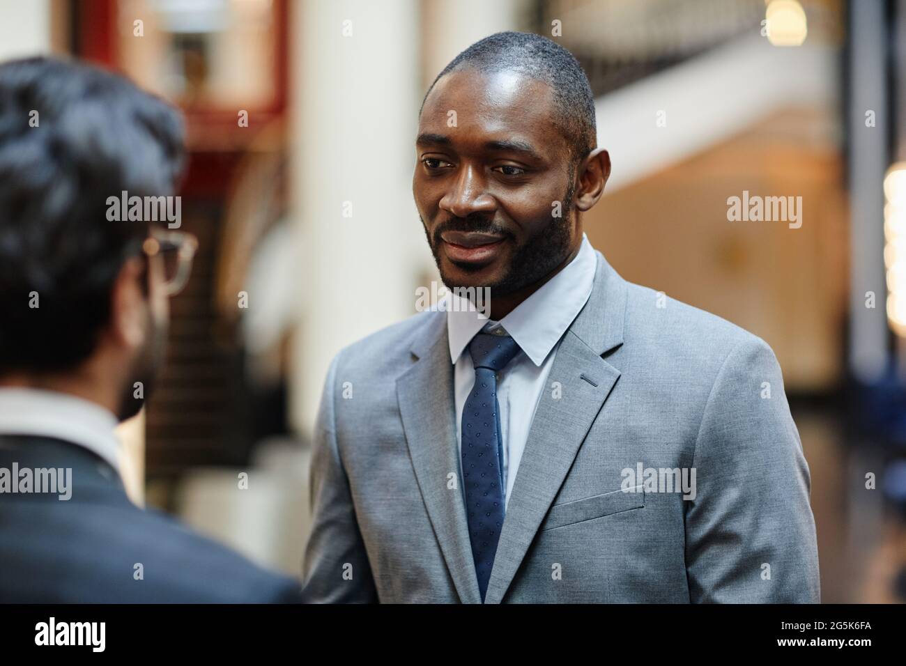 Ritratto di un uomo d'affari afro-americano di successo che parla con un partner mentre si trova nella hall dell'hotel Foto Stock