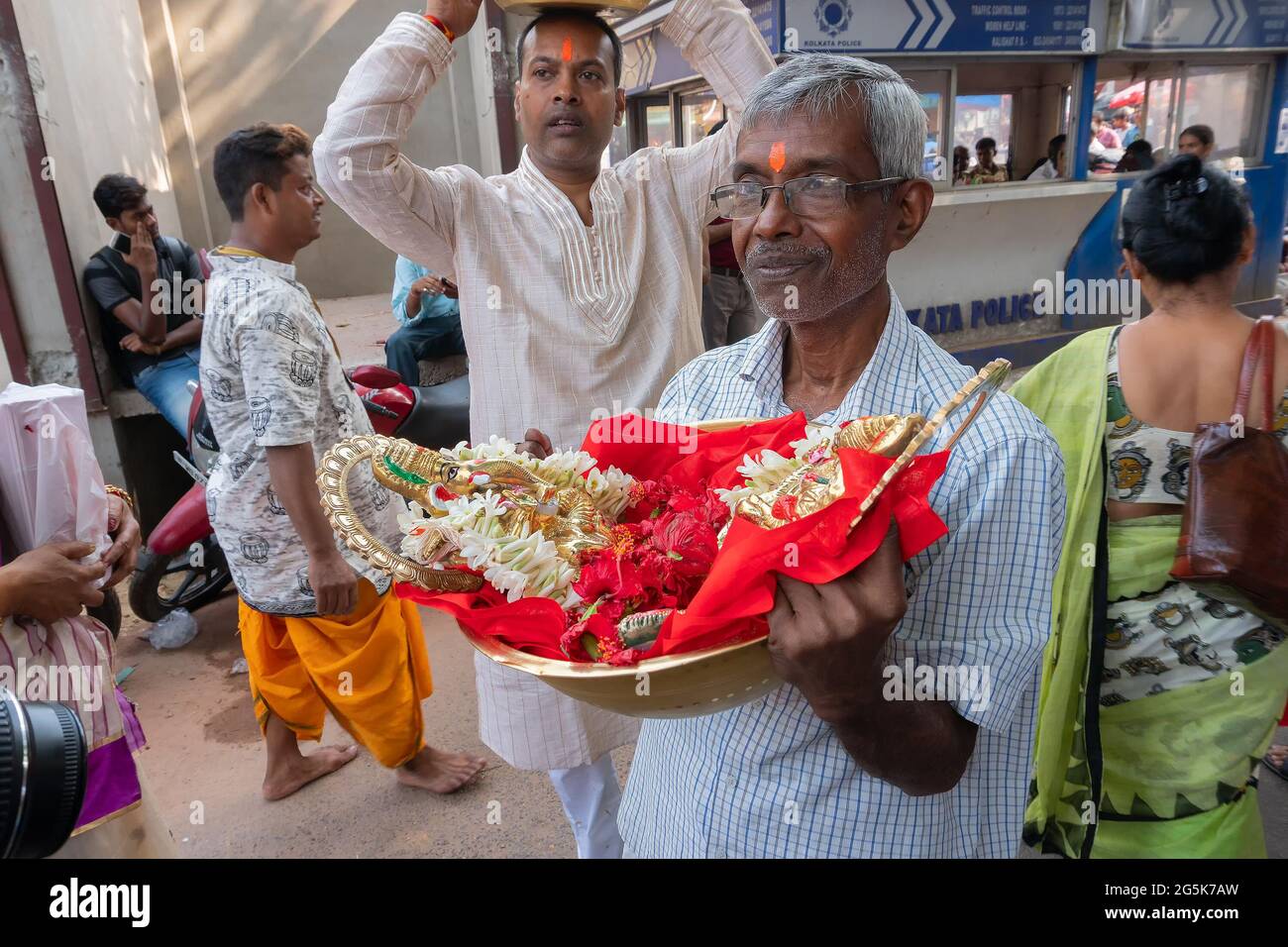 Kolkata, Bengala Occidentale, India - 15 Aprile 2019 : Vecchio che porta colorati idoli di argilla della Dea Laxmi e del Signore Ganesh per il culto, in un secchio di rame Foto Stock