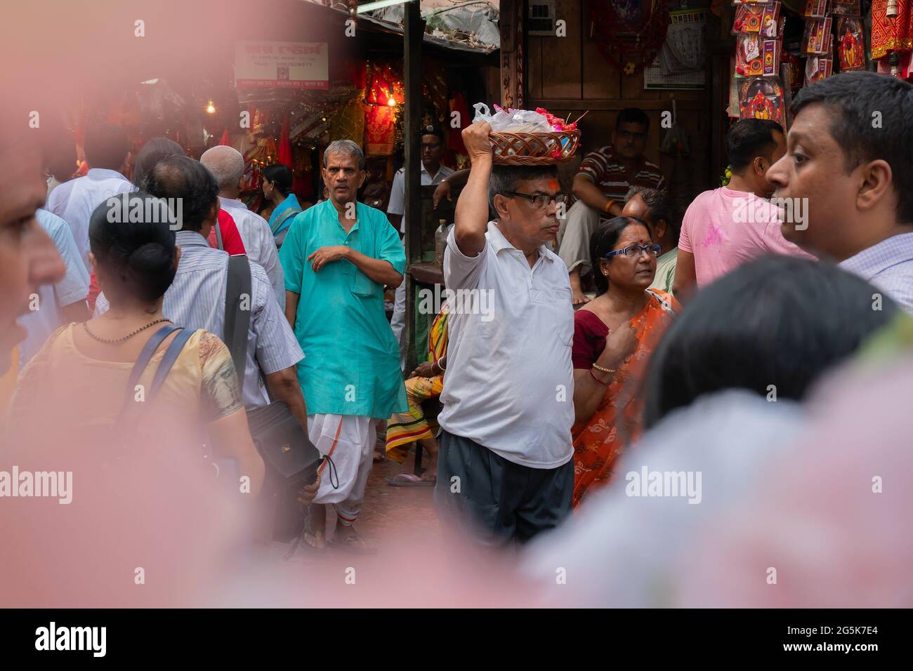 Kolkata, Bengala Occidentale, India - 15 Aprile 2019 : Vecchio che porta colorati idoli di argilla della Dea Laxmi e del Signore Ganesh per il culto, in un secchio. Immagine Foto Stock