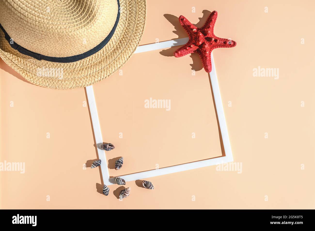 Appartamento estivo. cappello, stella marina, conchiglia e cornice quadrata bianca su sfondo Set Sail Champagne. Concept mare, vacanza. Vista dall'alto, con spazio copia Foto Stock