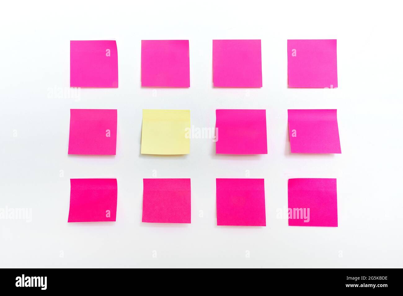 File di molte note colorate di carta adesiva rosa vuota e brillante e uno stativo di un tipo adesivo giallo stativo isolato su sfondo bianco testurizzato parete Foto Stock