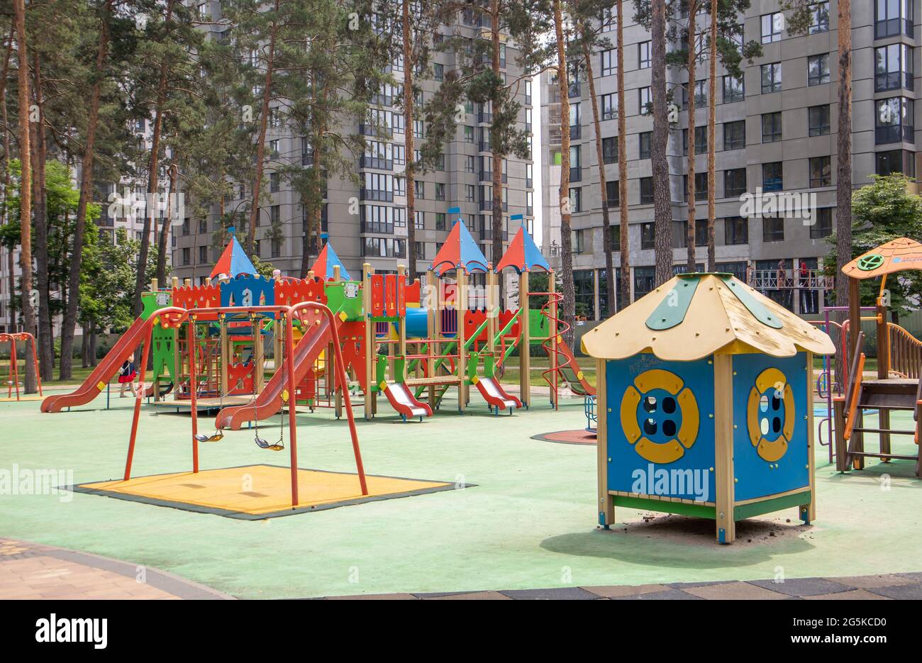 Un colorato e moderno parco giochi nel cortile in un parco senza persone. Swing, carosello esterno per bambini. Un parco giochi in un parco pubblico circondato Foto Stock