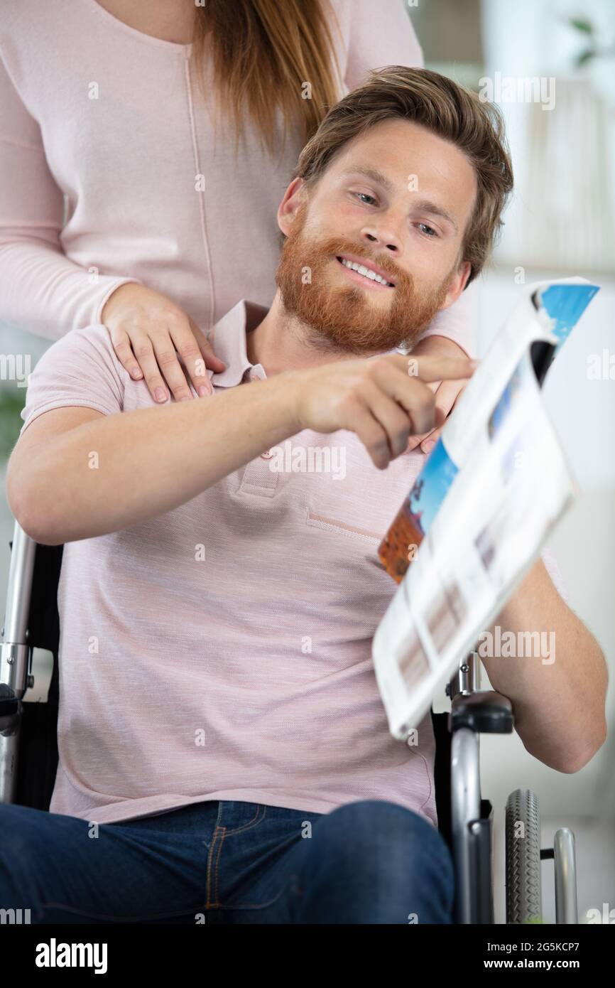 uomo disabile che mostra la brochure di viaggio alla sua ragazza Foto Stock