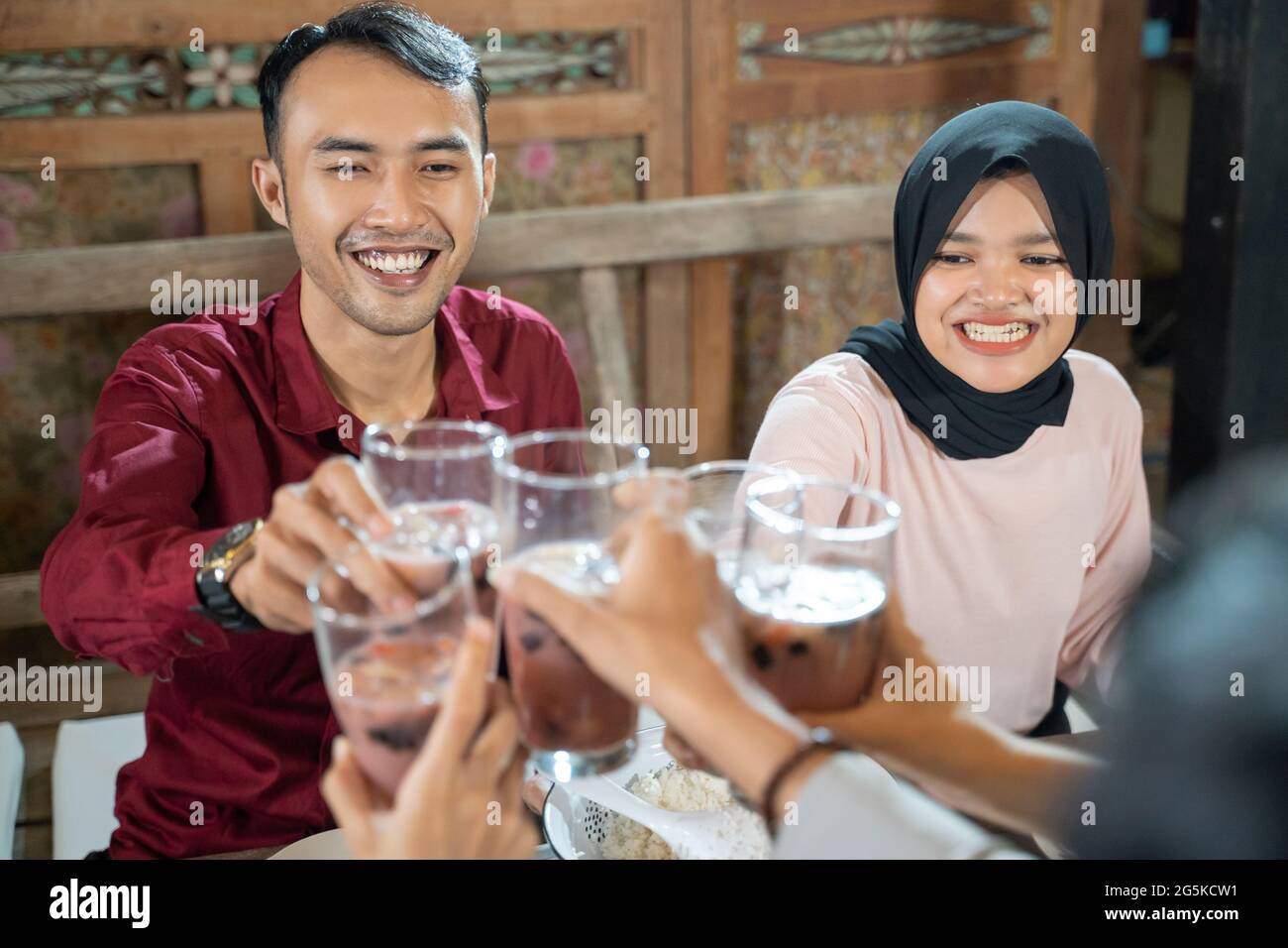 un paio di giovani festeggia e solleva bicchieri di ghiaccio di frutta per il pane tostato mentre si fracassano insieme Foto Stock