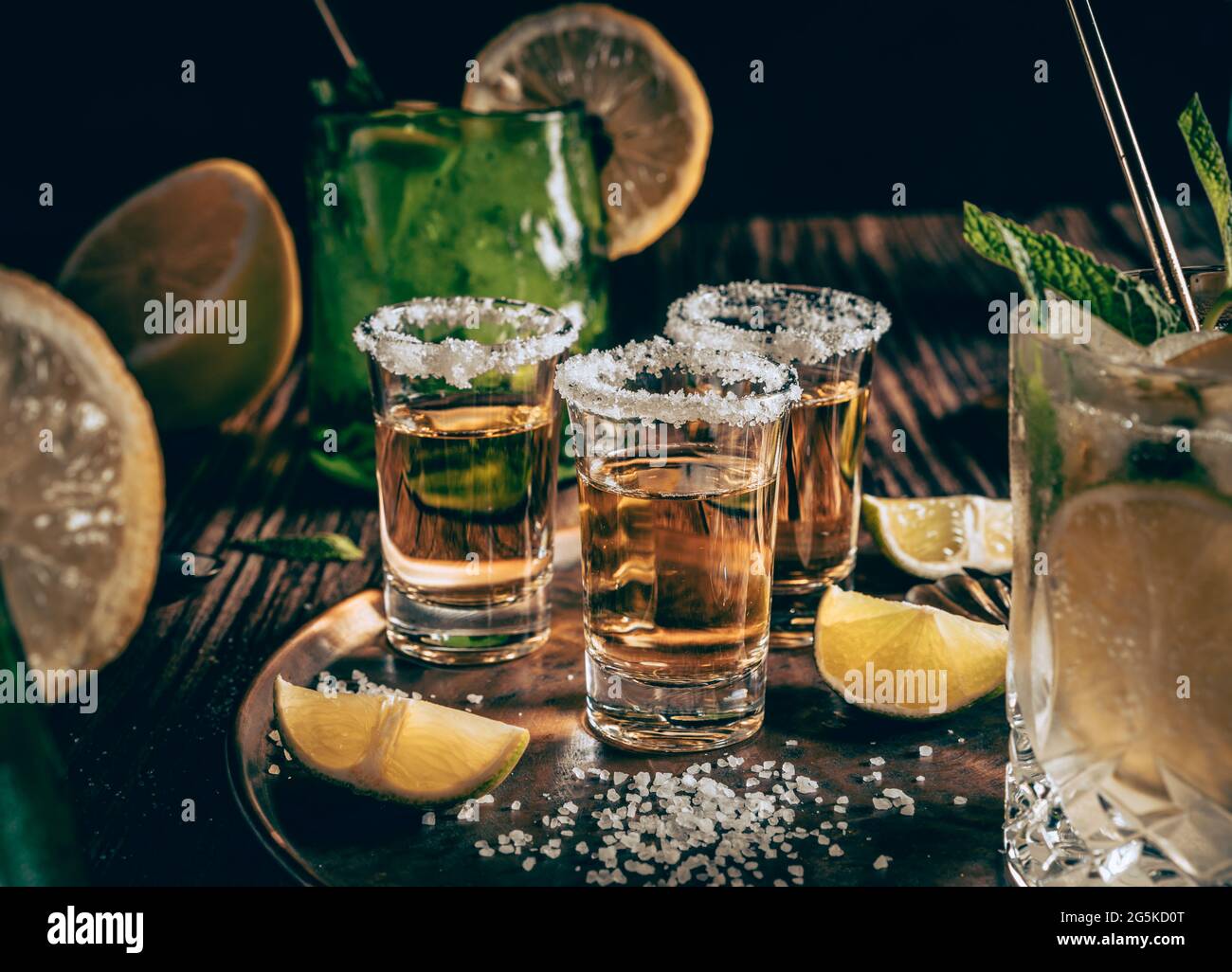 Fotografia scura di colpi di tequila con le fette del sale e del limone su una tavola di legno con copyspace. Foto Stock