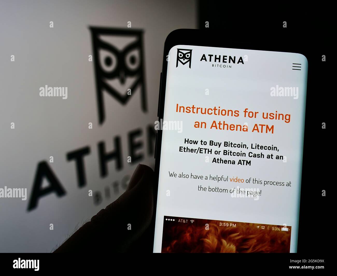 Persona che tiene il cellulare con pagina web della società americana di criptovaluta Athena Bitcoin sullo schermo davanti al logo. Mettere a fuoco il centro del display del telefono. Foto Stock